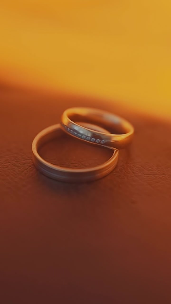 Bright flame flash over wedding rings on black background extreme closeup. Precious gold accessories for wife and husband. Eternal love and passion