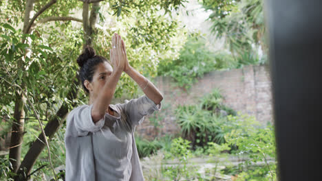 Focused-biracial-woman-practicing-yoga-on-terrace,-slow-motion-with-copy-space