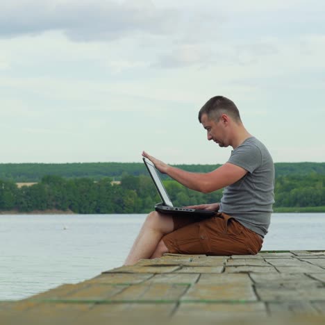 man on the pier working on a laptop. work on vacation