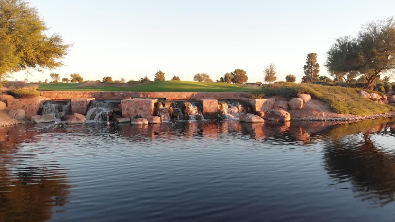 Riprese con drone di un campo da golf vicino a un quartiere residenziale in Arizona. Ripresa aerea bassa di uno specchio d'acqua sul campo