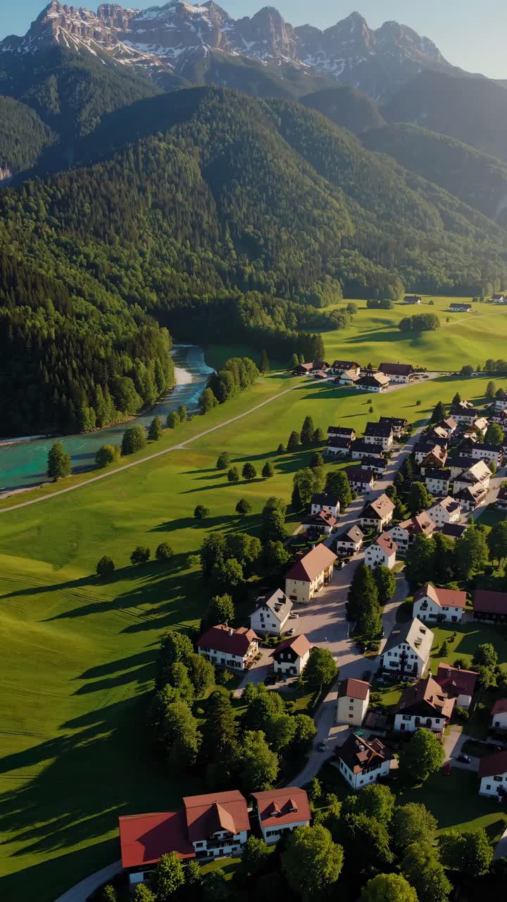 Video aereo di un pittoresco villaggio immerso in lussureggianti valli verdi con un fiume e montagne