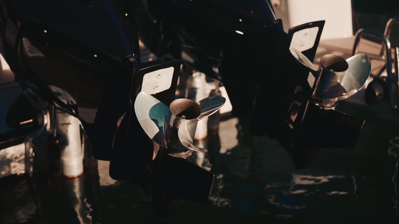 Close up of shiny metal boat propellers reflecting warm sunlight in a marina setting