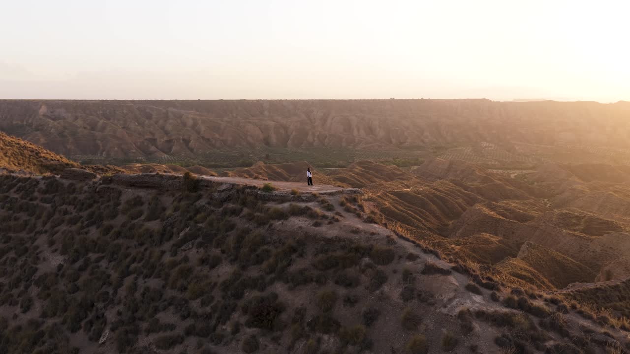 Person standing on a canyon ridge at sunset