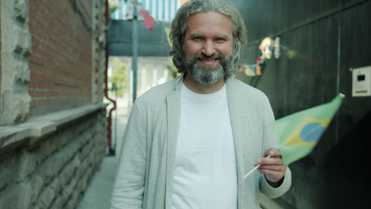 Smiling Man Holding Brazilian Flag in City Alley