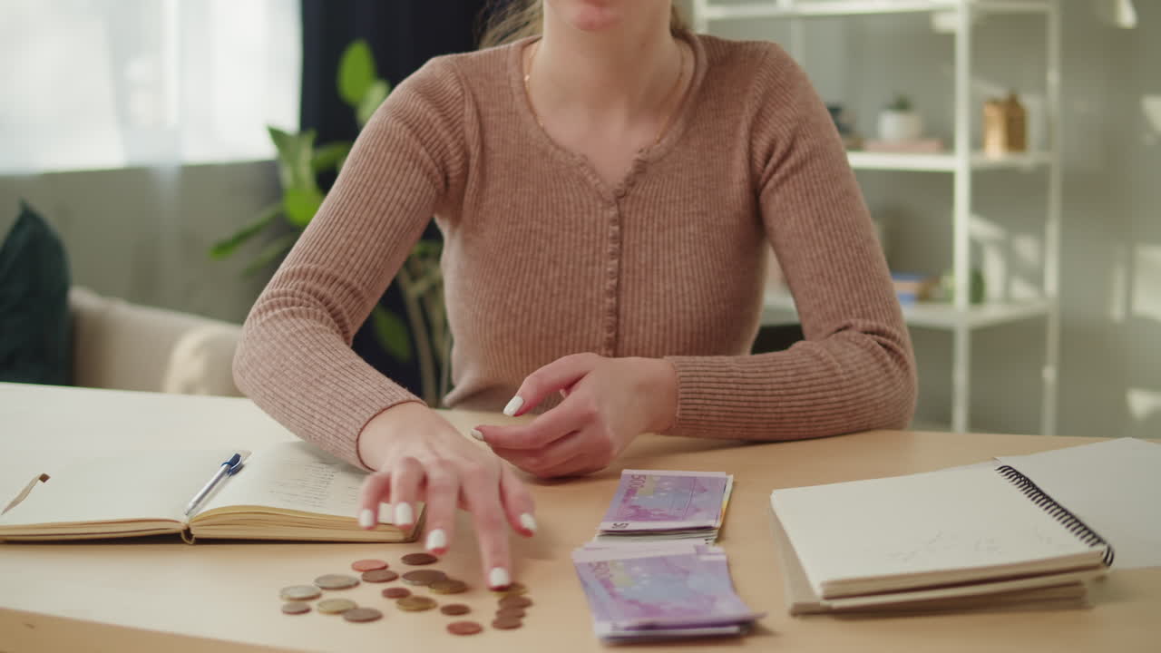 Mujer contando billetes y monedas de euro sobre un escritorio