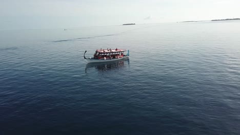 Spiral-drone-shot-of-a-boat-with-people-seating-in-yoga-positions-on-the-roof-top