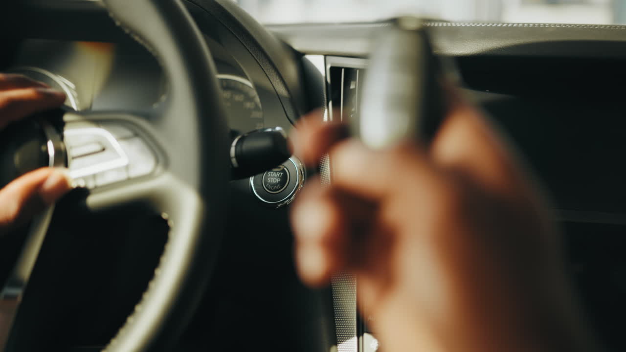 자동차 내부의 자동차 스티어링 과 자동차 열에 있는 사람의 손을 근접적으로 볼 수 있습니다.