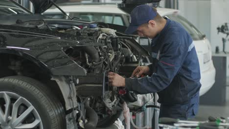 mechanic repairing car engine in auto workshop