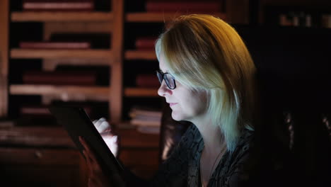 mujer rubia trabaja en tableta por la noche