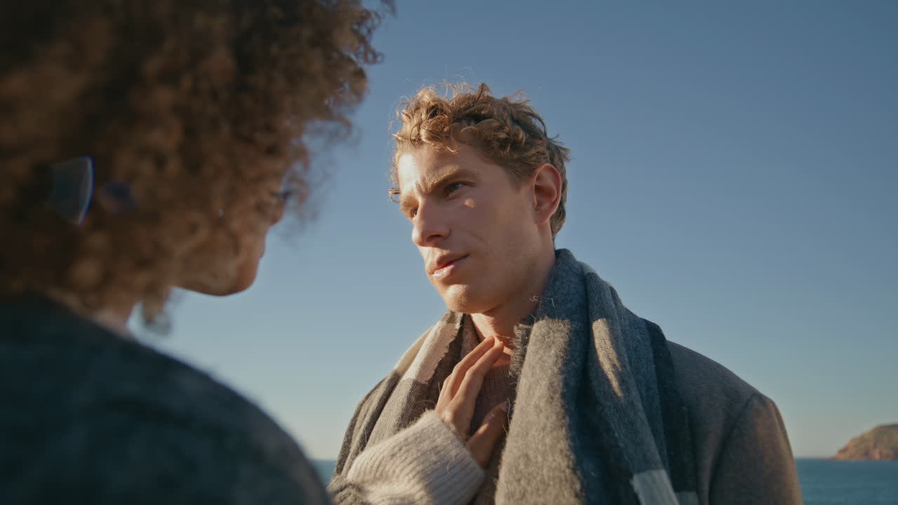 Curly woman touching man face hand at windy seashore closeup. Romantic moment