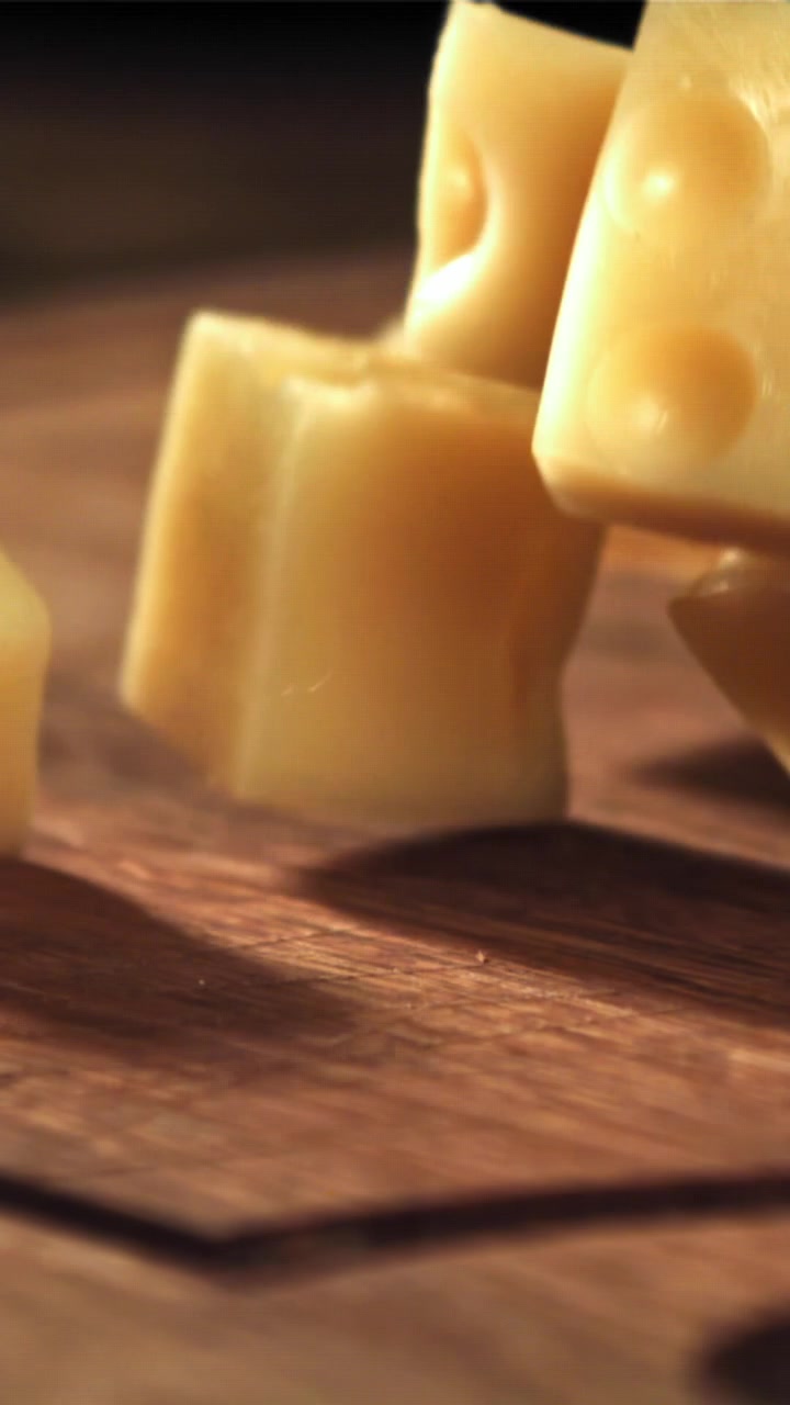 Dés de fromage tombant sur une surface en bois au ralenti