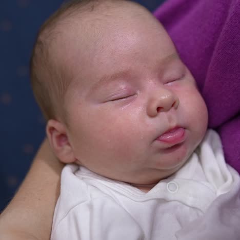 mommy's trying to wake her baby up by rubbing its cute cheek. baby continues to sleep not paying attention to mum's attempts. beautiful baby face close up