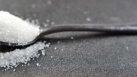 white sugar and spoon in a container on black background