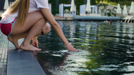 mujer tocando el agua en la piscina