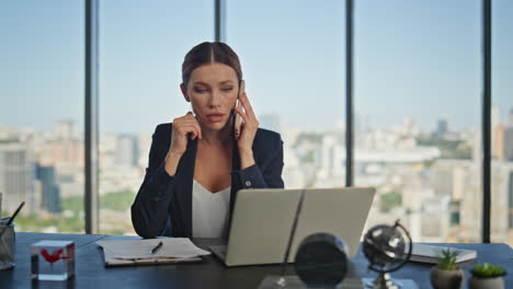 gerente financiero hablando teléfono inteligente en el escritorio. joven mujer de negocios trabajando portátil