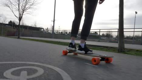 low angle track shot of skateboarder riding skateboard outdoors on asphalt bike road