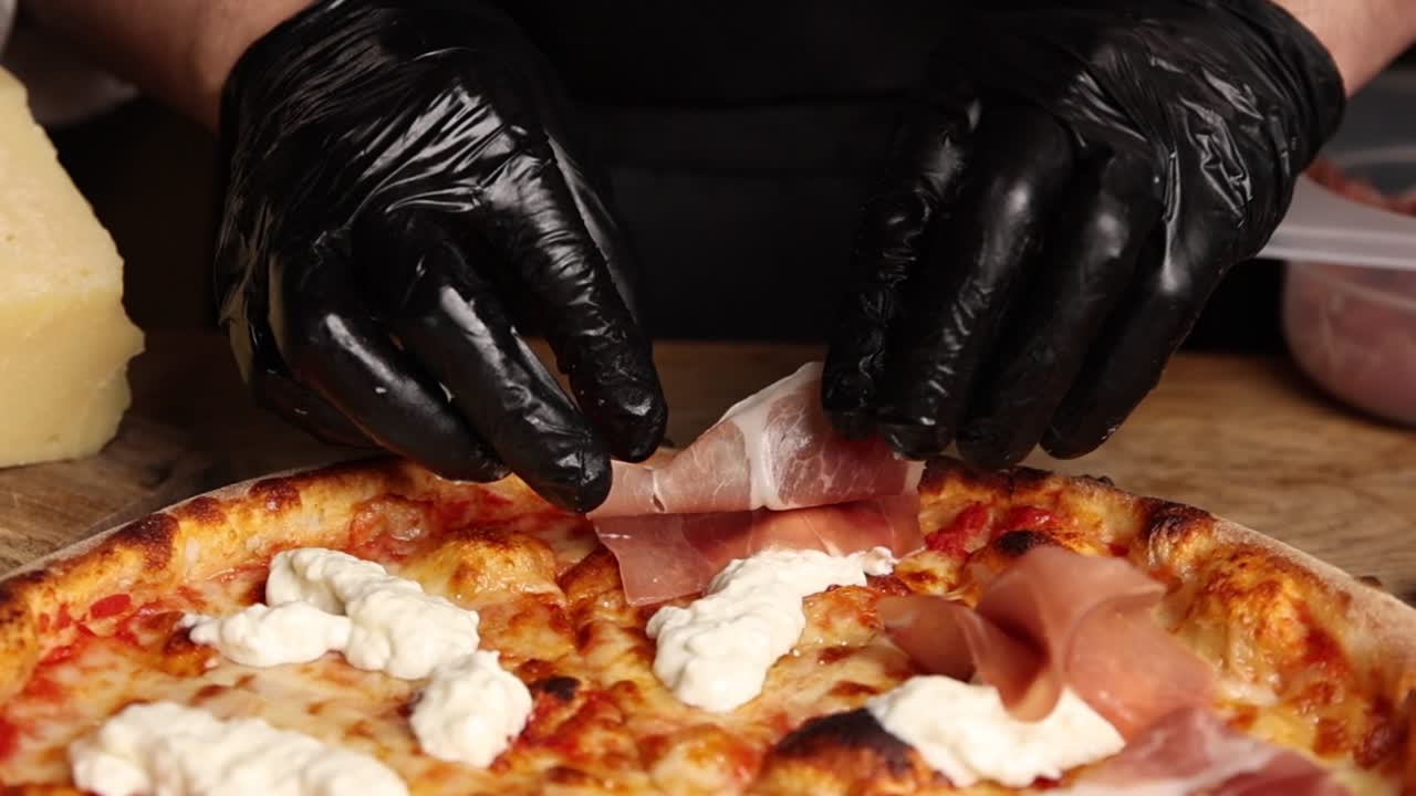 Chef aggiunge Prosciutto e Ricotta a pizza appena sfornata.