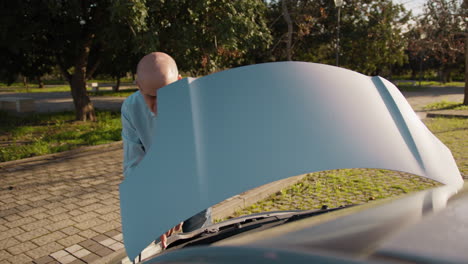 old man checks the engine condition of his car