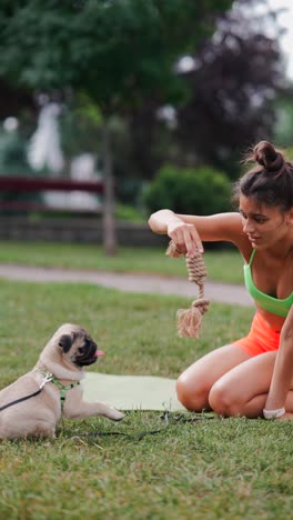 woman playing with pug dog in park