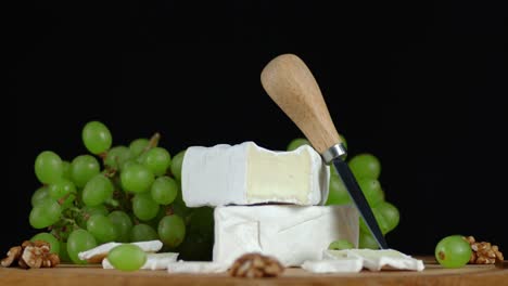 camembert cheese with a knife and grapes slowly rotating.