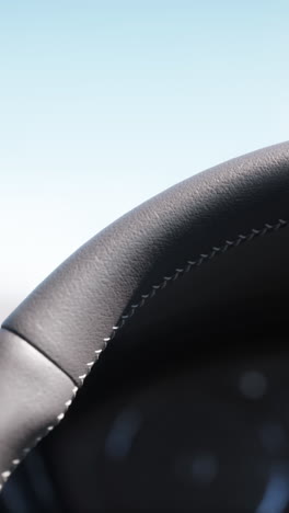 close up of a leather steering wheel with white stitching