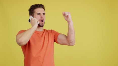 a young man celebrates good news on a phone call