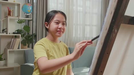 asian artist girl holding paintbrush mixed colour and painting on the canvas
