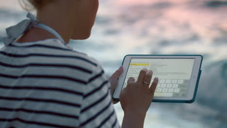 mujer con tablet por el mar en un día de viento