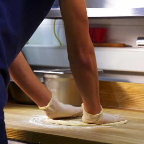 professional chef kneading floured dough for bread in bakery shop. man`s hands are forming the dough on a floured surface and kneading it with his hands