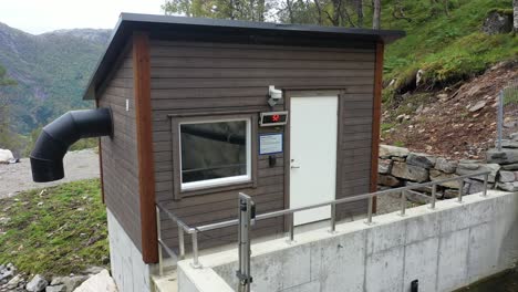 valve control house in mountain valley for control of waterflow to markaani hydroelectric powerplant - river minimum water flow in red display on wall - slow backward moving aerial