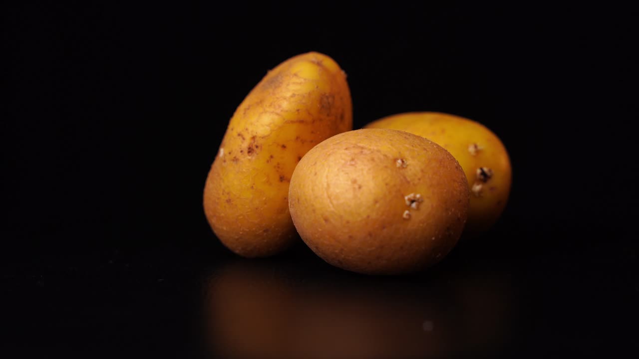 3 patatas contra un fondo negro girar