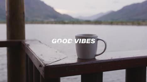 animation of good vibes text over cup of coffee at lake