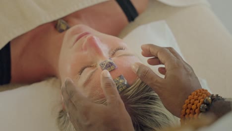 reiki healer cleansing energy of female laying on table with symbol stones