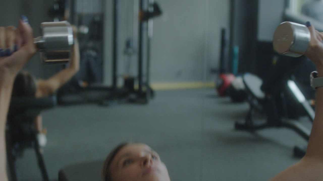Woman Doing Dumbbell Bench Press in Gym