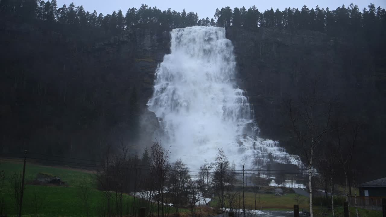 Slow motion captures massive flow of Tvindefossen waterfall during storm in Voss. Flooding and intense rainfall create powerful, dramatic water movement
