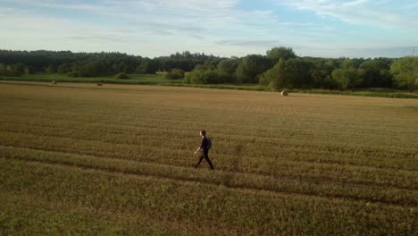 Hombre-Que-Viaja-Solo-Con-Una-Mochila-A-Través-De-Un-Paisaje-De-Campo-Desierto-Después-De-La-Cosecha