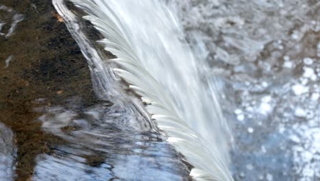 closeup on small splashing copper woodland river cascading into waterfall dolly birdseye right