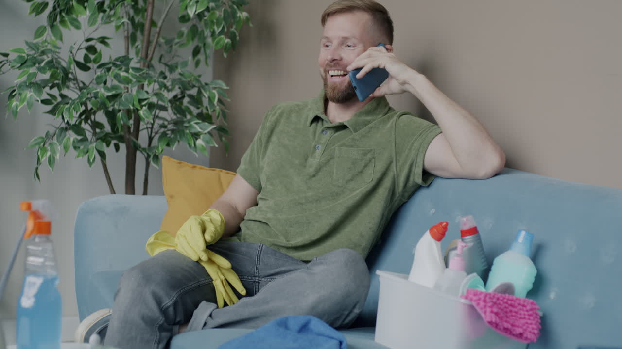 Man cleaning at home and talking on the phone
