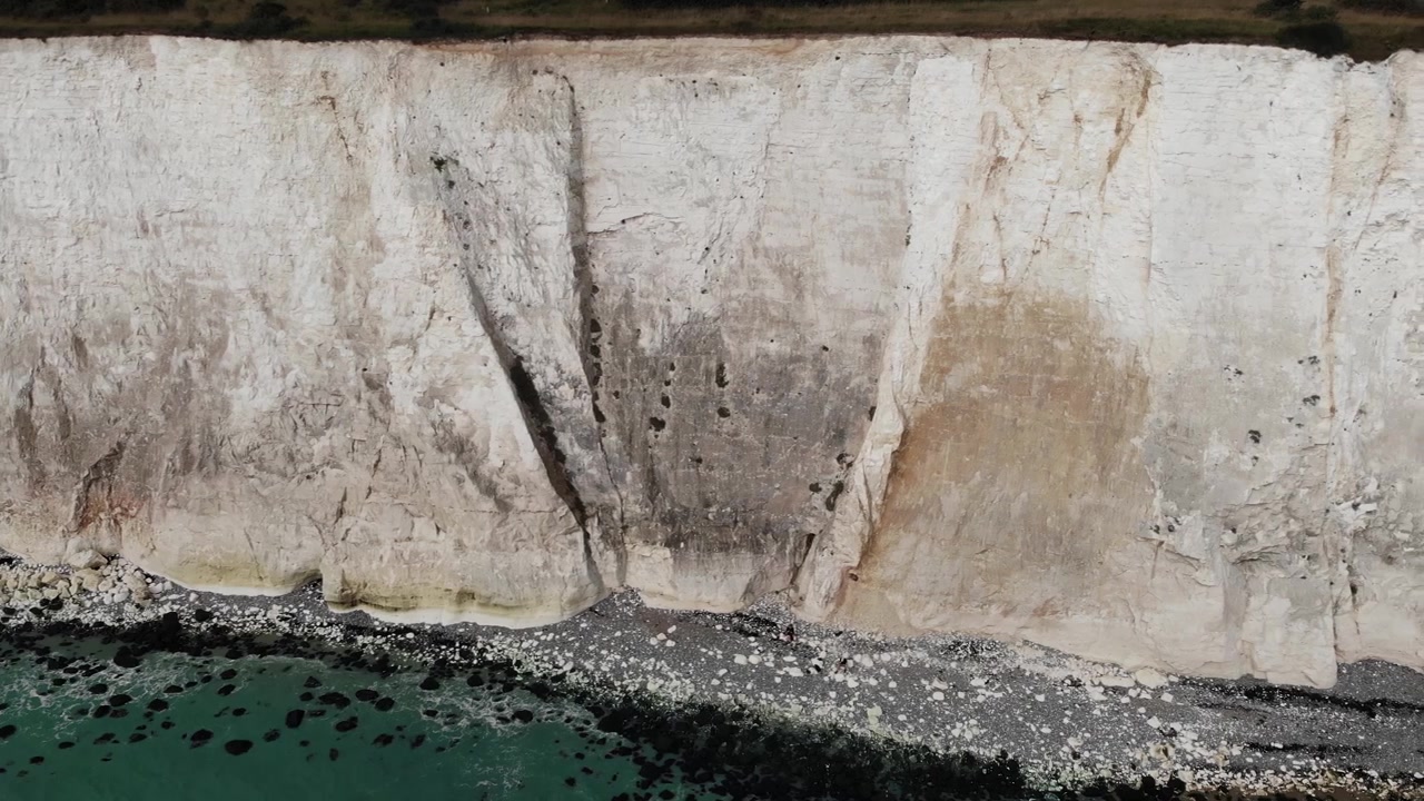 Drone Detail of Cliffs shot panning left to right over the White Cliffs of Dover, revealing the chalk coastline and turquoise sea in Kent, England, UK. Cinematic 4K video showing the landmark.