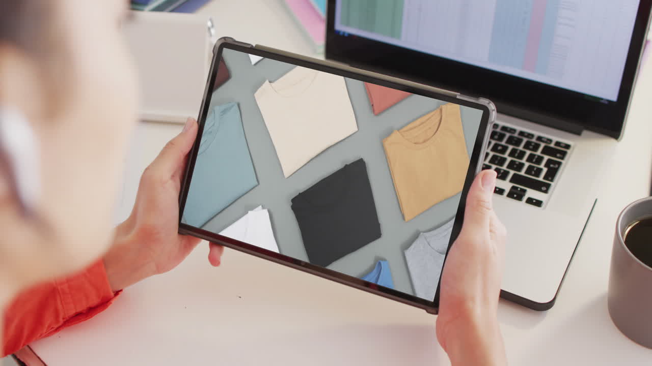 mujer caucásica en el escritorio usando tableta, compras en línea de ropa, cámara lenta