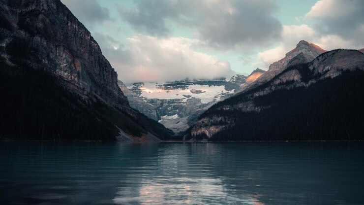 Canoe che navigano sul tranquillo Lago Louise nel Parco Nazionale di Banff in Alberta, Canada, sotto il cielo nuvoloso all'alba - Timelapse.