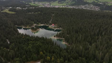 an aerial view showcases the tranquil beauty of lake caumasee, nestled in the mountainous forests of switzerland. surrounded by lush greenery, the serene waters reflect the vibrant landscape.