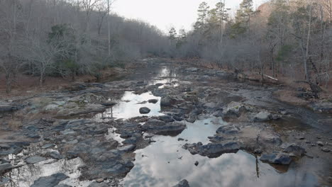 ominous scenery with calm shallow river and leafless woods in fall