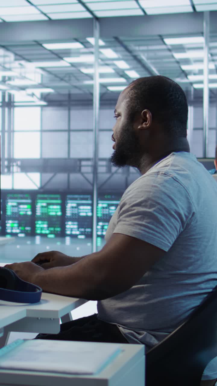 Afroamerikansk mann jobber på datamaskin i moderne datasenter
