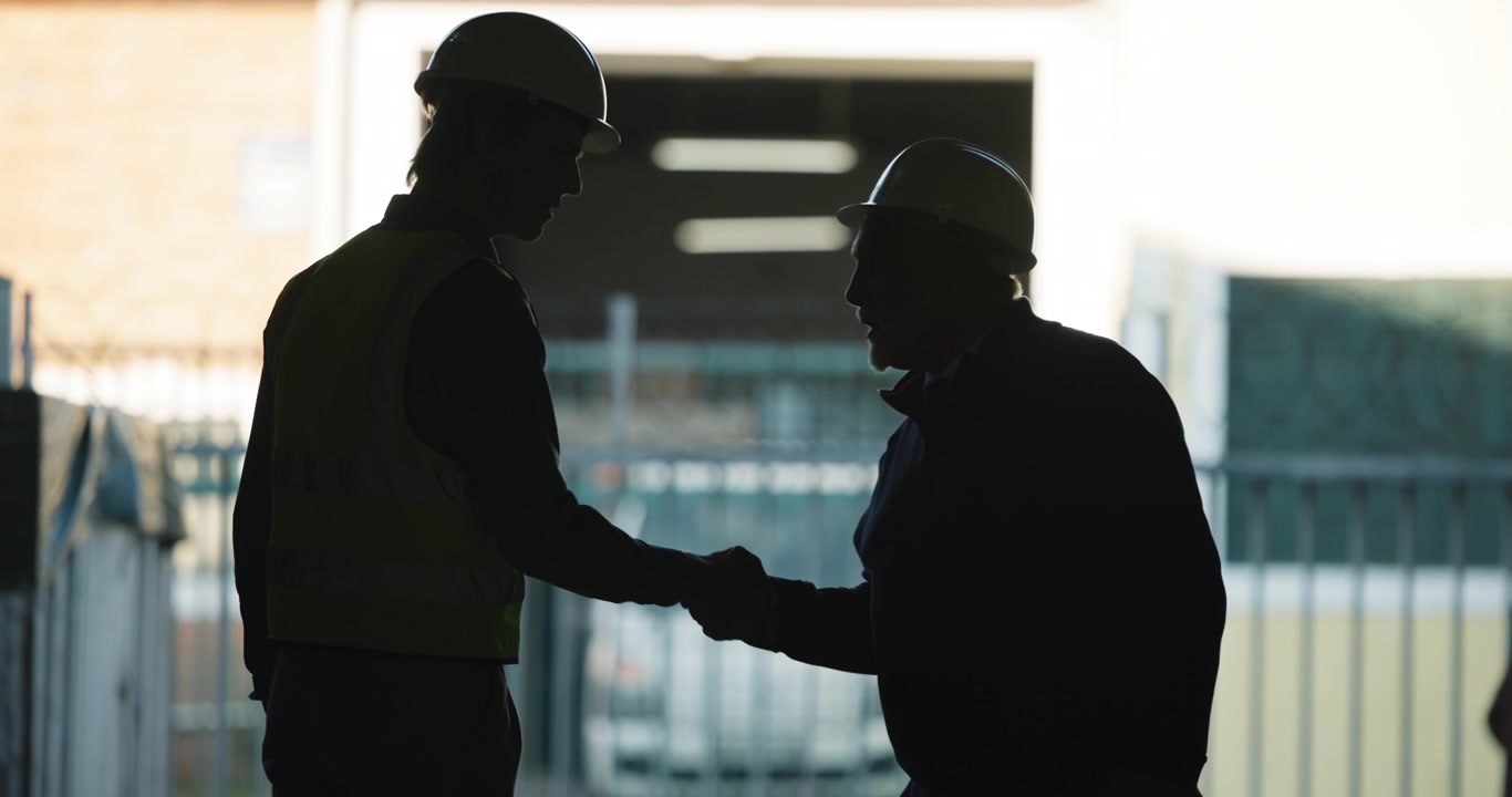 Two Construction Workers Shaking Hands in Silhouette