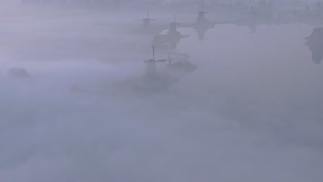 famous traditional windmills at holland during foggy morning, aerial