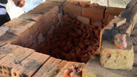 tight overview of potter removing southeast asian clay figurines in drying kiln, than ha hoi an vietnam