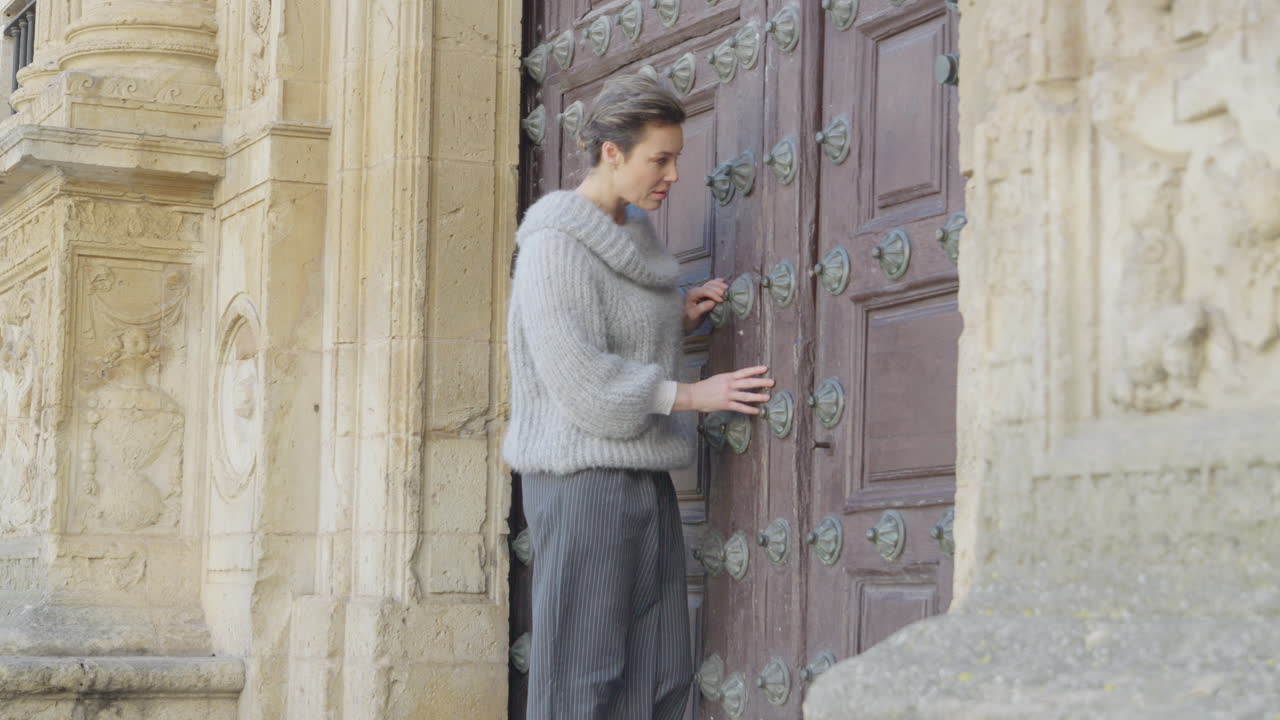 Adult Woman Inspects Closed Old Wooden Door of Monumental Building