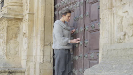 Adult Woman Inspects Closed Old Wooden Door of Monumental Building