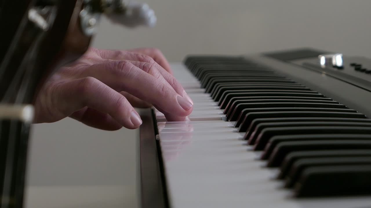 Playing piano keyboard with guitar next to it, playing music in studio close up